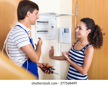 Young Smiling Woman And Repairman Near Electric Meter In Domestic Interior