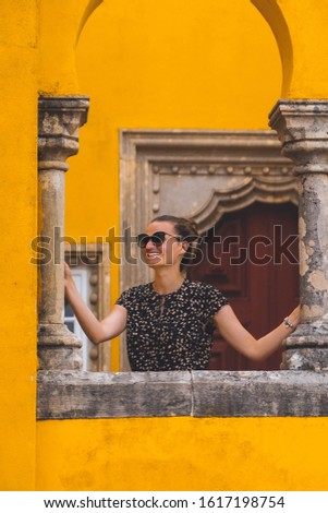 Young smiling  woman in sunglasses enjoying summer view of Pena Castle in Sintra, Portugal.