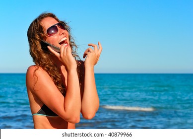 Young Smiling Woman Talking By Phone On A Beach