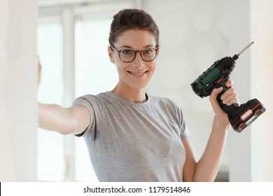 Young Smiling Woman Using A Drill, Home Renovation And DIY Concept