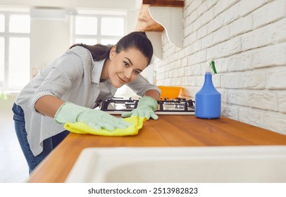 Young smiling woman washing kitchen table with rag and detergent disinfecting her apartment. Girl housewife cleaning surface of counter. Domestic chores, housework and household concept. - Powered by Shutterstock