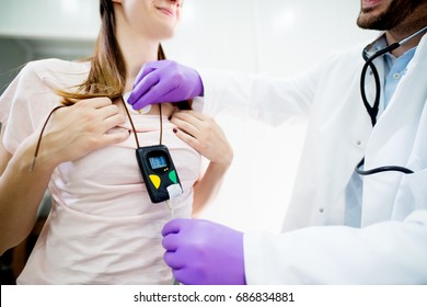 Young Smiling Woman Wearing A Holter Heart Monitor.