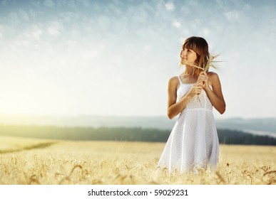 Young smiling woman in white dress standing in field - Powered by Shutterstock