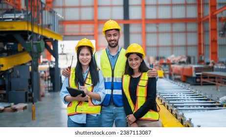 Young and smiling young woman worker in modern industrial factory or factory in work clothes and helmet standing in large factory. - Powered by Shutterstock