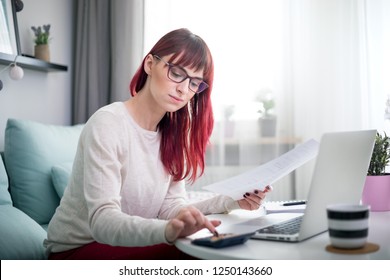 Young smiling woman working at home using laptop while sitting on sofa - Shutterstock ID 1250143660