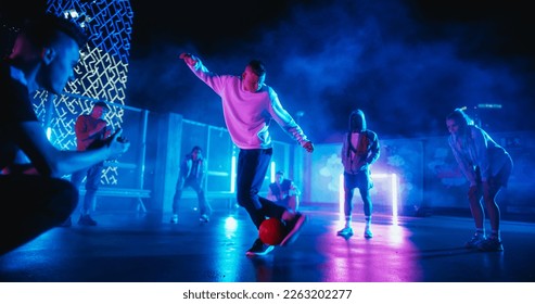 Young Soccer Athlete Performing Freestyle Tricks with a Ball. Footballer Showing Off Juggling Skills. Urban City Spot with Neon Lights, Graffiti on Walls and Scenery with Skyscrapers at Night - Powered by Shutterstock