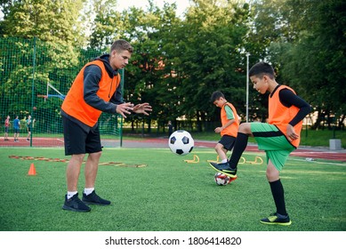 Young soccer coach instructs teen players. A young professional coach trains the ball kicks with young football players.