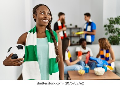 Young soccer hooligan woman wearing team scarf holding football ball at home - Shutterstock ID 2075785762