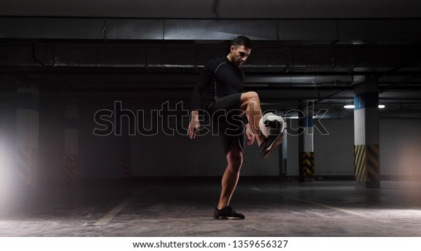 A young soccer man training\
the basic tricks with the ball Balancing the ball on the lifted\
feet