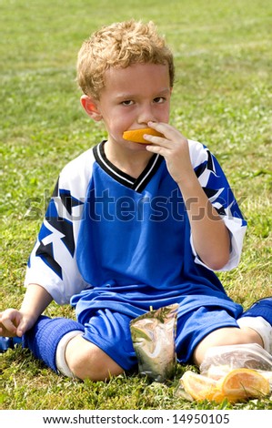 Young soccer player having halftime snack of orange and drink pouch