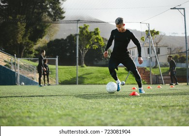 Young soccer player training in football field with team in background. Five a side football team practicing on field outdoors. - Powered by Shutterstock