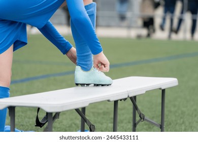 Young soccer player tying shoelaces before match. Close-up of boy tying football cleats on field.High quality photo - Powered by Shutterstock