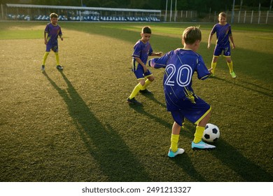 Young soccer players, boys in blue uniforms practicing passing ball skills, training soccer game on sunny field, demonstrating enthusiasm. Concept of sport, childhood, education, active lifestyle - Powered by Shutterstock