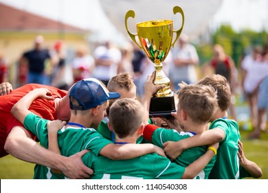 Young Soccer Players Holding Trophy. Boys Celebrating Soccer Football Championship. Winning Team Of Sport Tournament For Kids Children.