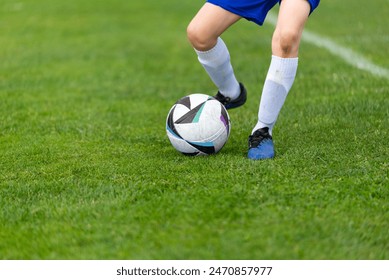 Young soccer player's kick ball. Ball and legs in sharp focus on a lush green field close-up - Powered by Shutterstock