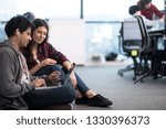young software developers couple using laptop computer writing programming code while sitting on the floor at modern creative startup office