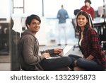 young software developers couple using laptop computer writing programming code while sitting on the floor at modern creative startup office