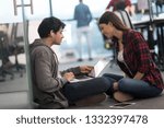 young software developers couple using laptop computer writing programming code while sitting on the floor at modern creative startup office