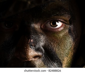 young soldier face with jungle camouflage paint