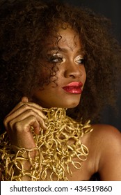 Young South African Woman In Gold Makeup And Accessories With A Pensive, But Sly Expression