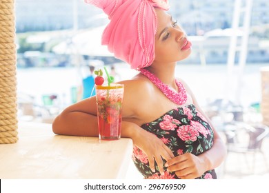 Young South African Zulu Woman Is Sitting Near Bar And Drinking Mojito, Summer Time With Fashion Makeup Is Wearing Pink Turban Fashion Dress And Bead