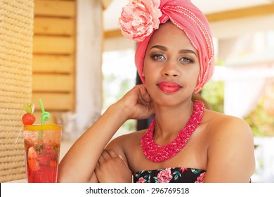 Young South African Zulu Woman Is Wearing Fashion Dress With Makeup Is Sitting Near Bar And Drinking Mojito, Summer Time 