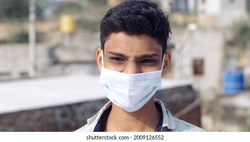 A Young South Asian Boy Wearing A White Medical Coronavirus Mask With A Blurry Background