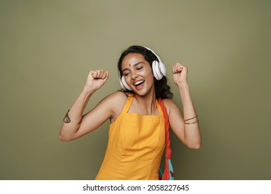 Young South Asian Woman Dancing While Listening Music With Headphones Isolated Over Green Wall