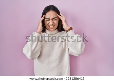 Young south asian woman standing over pink background with hand on head, headache because stress. suffering migraine. 