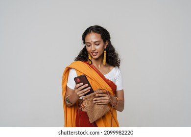 Young South Asian Woman Wearing Sari Smiling While Using Mobile Phone Isolated Over White Wall