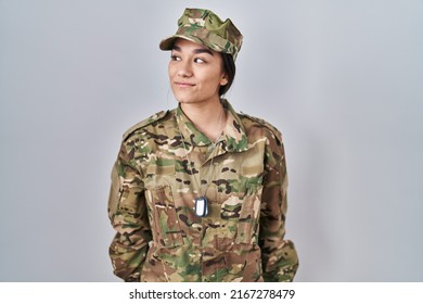 Young South Asian Woman Wearing Camouflage Army Uniform Smiling Looking To The Side And Staring Away Thinking. 