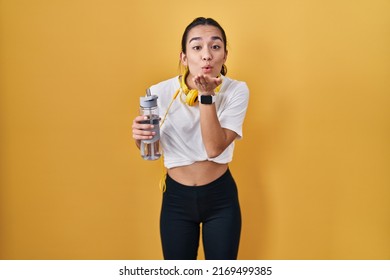 Young south asian woman wearing sportswear drinking water looking at the camera blowing a kiss with hand on air being lovely and sexy. love expression.  - Shutterstock ID 2169499385