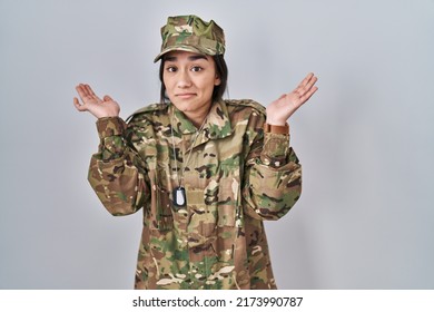 Young South Asian Woman Wearing Camouflage Army Uniform Clueless And Confused Expression With Arms And Hands Raised. Doubt Concept. 