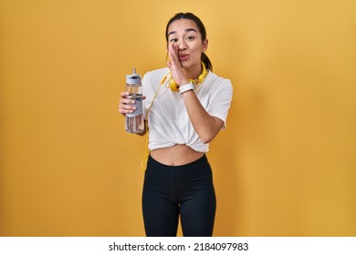 Young South Asian Woman Wearing Sportswear Drinking Water Hand On Mouth Telling Secret Rumor, Whispering Malicious Talk Conversation 