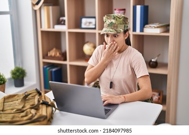 Young South Asian Woman Wearing Camouflage Army Uniform Doing Video Call Covering Mouth With Hand, Shocked And Afraid For Mistake. Surprised Expression 