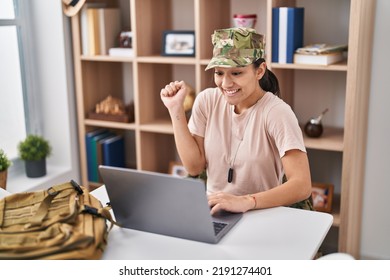 Young South Asian Woman Wearing Camouflage Army Uniform Doing Video Call Screaming Proud, Celebrating Victory And Success Very Excited With Raised Arm 