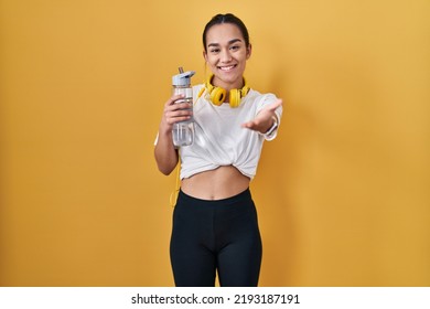 Young South Asian Woman Wearing Sportswear Drinking Water Smiling Friendly Offering Handshake As Greeting And Welcoming. Successful Business. 