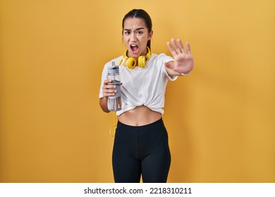 Young south asian woman wearing sportswear drinking water doing stop gesture with hands palms, angry and frustration expression  - Shutterstock ID 2218310211