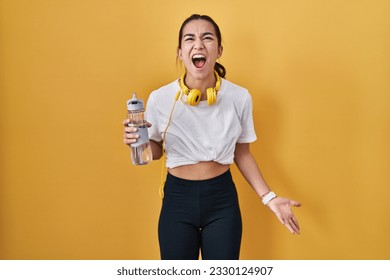 Young south asian woman wearing sportswear drinking water angry and mad screaming frustrated and furious, shouting with anger. rage and aggressive concept.  - Shutterstock ID 2330124907