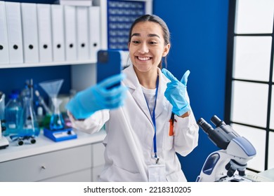 Young South Asian Woman Working At Scientist Laboratory With Smartphone Smiling Happy Pointing With Hand And Finger 