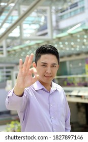 Young South East Asian Man Business Office Outdoor Stand Look At Camera Ok Finger Sing Gesture Happy