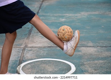 Young southeast asian female sepak takraw player using her right ankle to hold ball up on the serving center area of the court, outdoor sepak takraw playing after school, soft and selective focus. - Shutterstock ID 2214997711