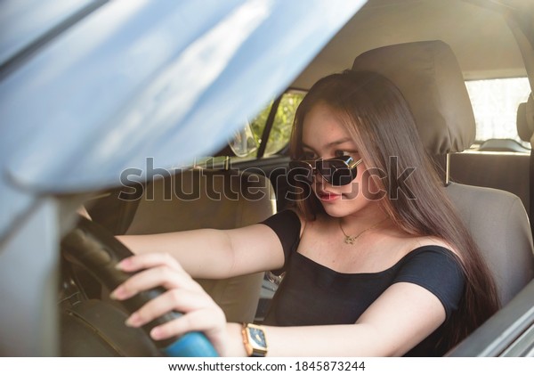 A\
young southeast asian lady is focused and attentive in driving.\
Driving safely. Serious look and mood. Afternoon\
shot.
