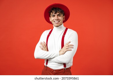 Young Spanish Latinos Attractive Handsome Serious Stylish Fashionable European Man 20s In Hat White Shirt Trousers With Suspenders Hold Hands Crossed Folded Isolated On Red Background Studio Portrait