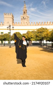 Young Spanish Man In Black Shirt, Jacket And Pants, With Dancing Shoes, Dancing Flamenco With Black And Gold Capote In The Street. Typical Spanish Concept, Art, Dance, Culture, Tradition.