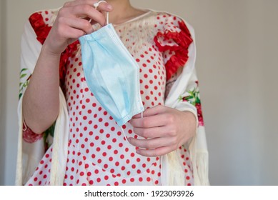 Young Spanish Woman Wearing A Red Flamenco Dress And A White Manila Shawl. She Is Holding A Blue Disposable Mask