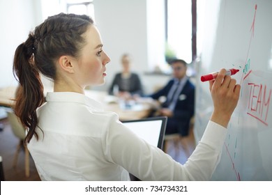 Young speaker with red highlighter explaining her vision of teamwork on whiteboard