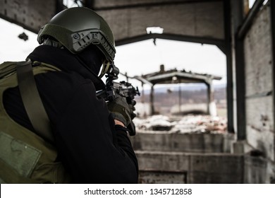 Young Special forces SWAT soldier aiming with assault rifle gun at the ruined building war terrorist battle zone airsoft