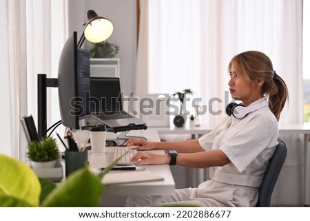  Young IT specialist woman checking debugging system on large curved monitor, working in startup company office