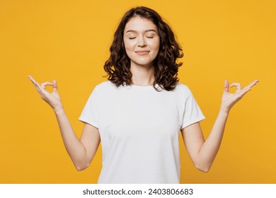 Young spiritual woman wear white blank t-shirt casual clothes hold spreading hands in yoga om aum gesture relax meditate try to calm down isolated on plain yellow orange background. Lifestyle concept - Powered by Shutterstock